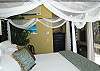 Air conditioning, luxury linens, an in suite bathroom, a king sized four poster bed, and a convenient corner desk for writing post cards all  dot the spacious master bedroom.