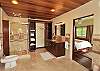Two wooden doors separating the bedroom to its spacious ensuite bath with single vanity, big tiled shower and bathtub, and walk in closet