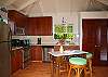 The fully equipped kitchen boasts stainless steel appliances and a granite topped island with stools for kitchen helpers.