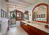 The sumptuous master bath features a double vanity, a separate WC with a bidet, and a semi-alfresco double shower clad in glass tile and travertine.