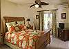 On the lower level, this queen sized sleigh bed faces the covered porch. Guests have direct access to the pool from this warm tropical bedroom.