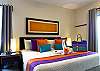 Bright bedroom with a comfortable king bed, soft linens, bedside lamps, and colorful accents for a relaxed night’s sleep.
