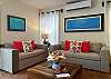 Living room inside Abbey del Sol A2 Unit 10, a Puerto Morelos vacation rental, featuring two sofas, a wooden coffee table, colorful accent pillows, wall art, and a bright, comfortable space for relaxing after a day at the beach.