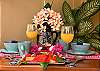 Balcony table detail at Abbey del Sol A2 Unit 10, a Puerto Morelos vacation rental, featuring colorful place settings, flowers, fresh drinks, tropical plants, and a welcoming outdoor dining feel.