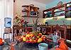 Kitchen and dining area inside Abbey del Sol A2 Unit 10, a Puerto Morelos vacation rental, featuring a dining table with fruit and place settings, wood cabinetry, open shelving, and a well-equipped kitchen for a comfortable stay.
