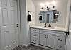 This full bathroom is situated between the primary bedroom and the kid's suite. It features a large vanity and updated tile shower with two overhead shower heads.