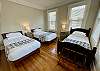 The first bedroom has three single beds.