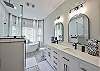 This gorgeous bathroom has a waterfall shower and large soaking tub as well as a double sink vanity.