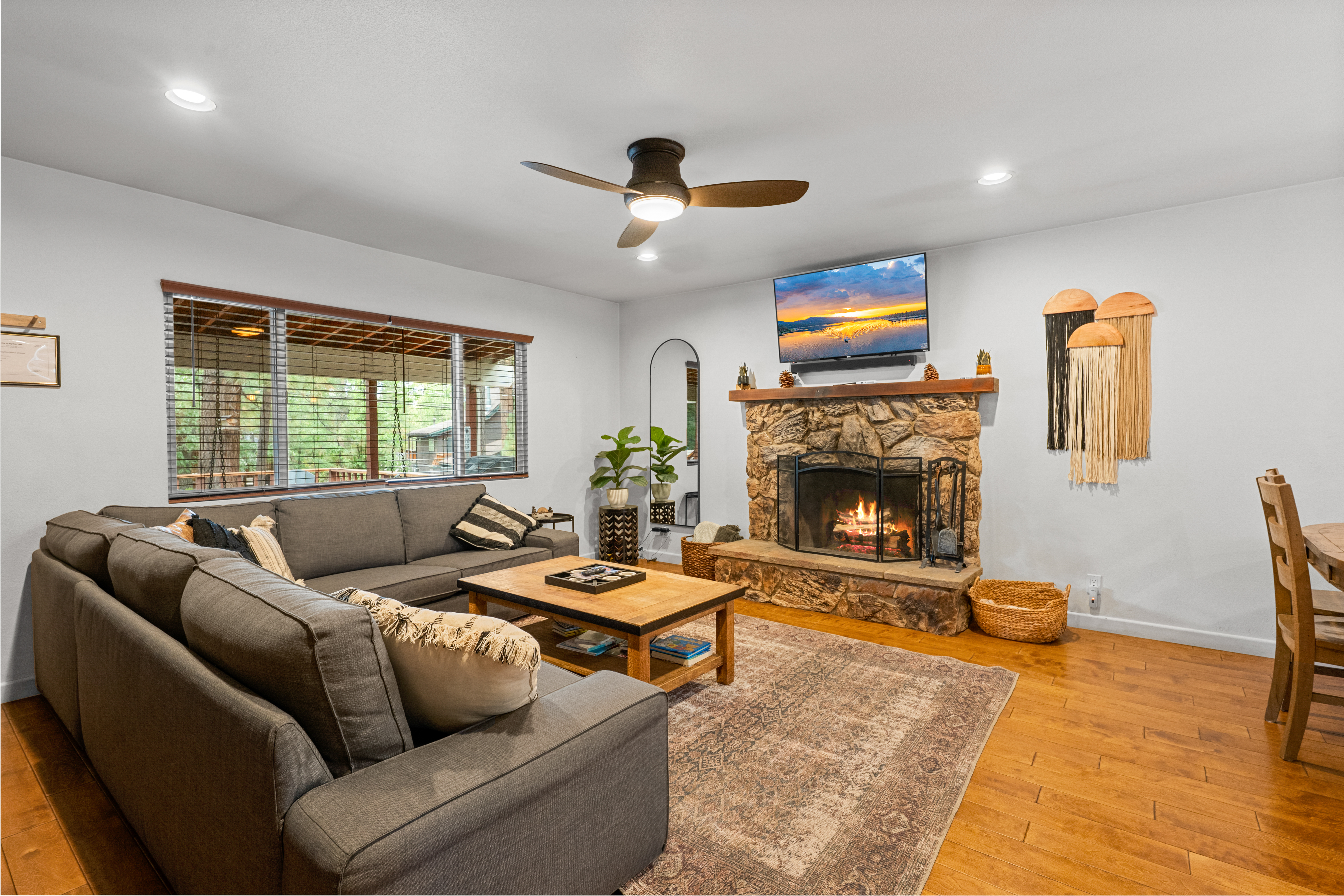 Living room area with rock fireplace is complete with a sectional sofa & flat-screen TV to allow everyone to kick back in style.
