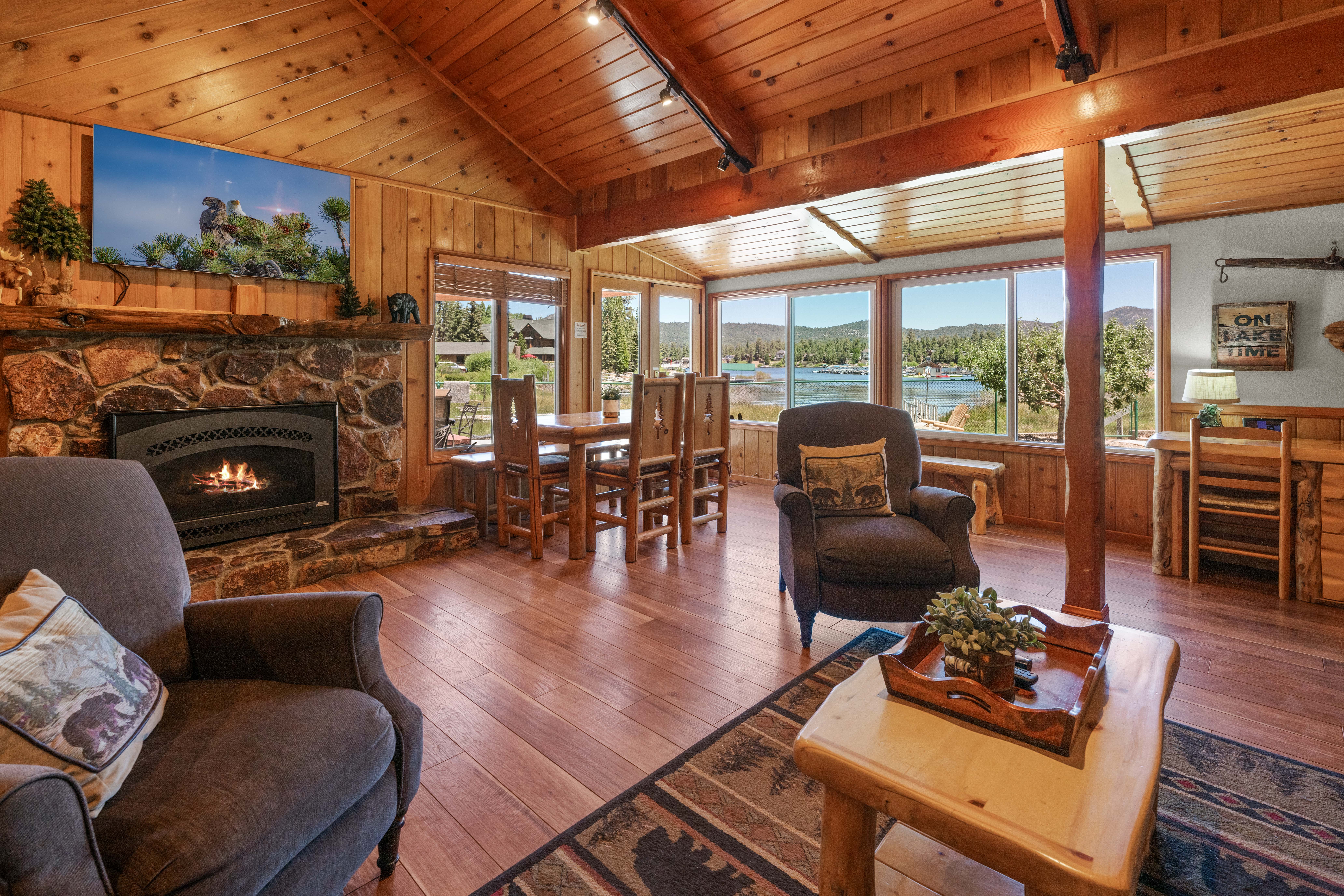 The living room is cozy & charming w/mountain décor & comfortable furniture. This space includes a gas fireplace, dining area w/table, 55" Smart TV, lovely lake & mountain views & French doors to the backyard patio.
