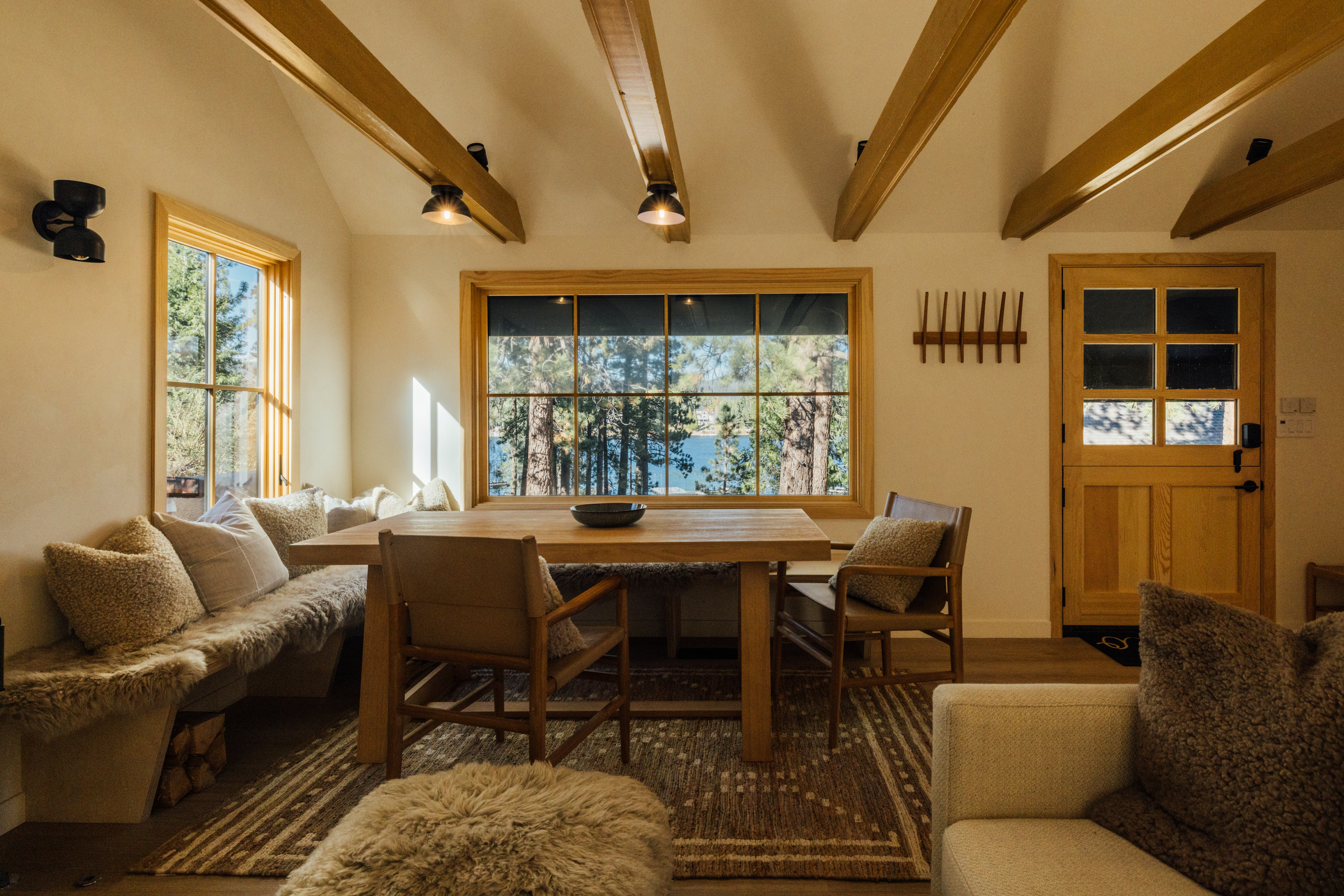 The cabin features vaulted ceilings, exposed beams, and a preserved stone fireplace that anchors the living space. The design blends modern comfort with natural materials, creating a warm and elevated atmosphere throughout.