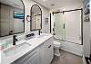 Well-lit guest bath with a double vanity and the shower-tub combo.