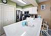 The kitchen of this one-bedroom unit has several nice features, including tiled countertops, Mr. Coffee and Keurig coffee makers and two-sided sink with pull out sprayer. 3 chairs at the island provide additional seating