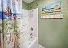 The small beach paintings on the wall and beachy shower curtain give the space a bit of added color.