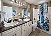 The Master Bathroom has some nice features, with a double-sink counter, a white linen cabinet, and a flexible massage showerhead in the bath. The cabinets and countertop have been upgraded to match the kitchen fixtures