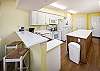 This bright, white kitchen has all the necessities including a microwave, coffee maker, and a blender.