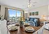 The open-concept living and kitchen area is designed for comfort and connection, featuring cozy seating, a fully equipped kitchen, and stunning beachfront views that flow in through large windows.