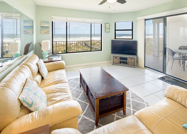 Spacious living room with open floor plan and connected balcony featuring a direct view of the ocean.