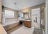 Primary bathroom ensuite with two separate sinks, bathtub with jets, separate shower, and walk-in closet