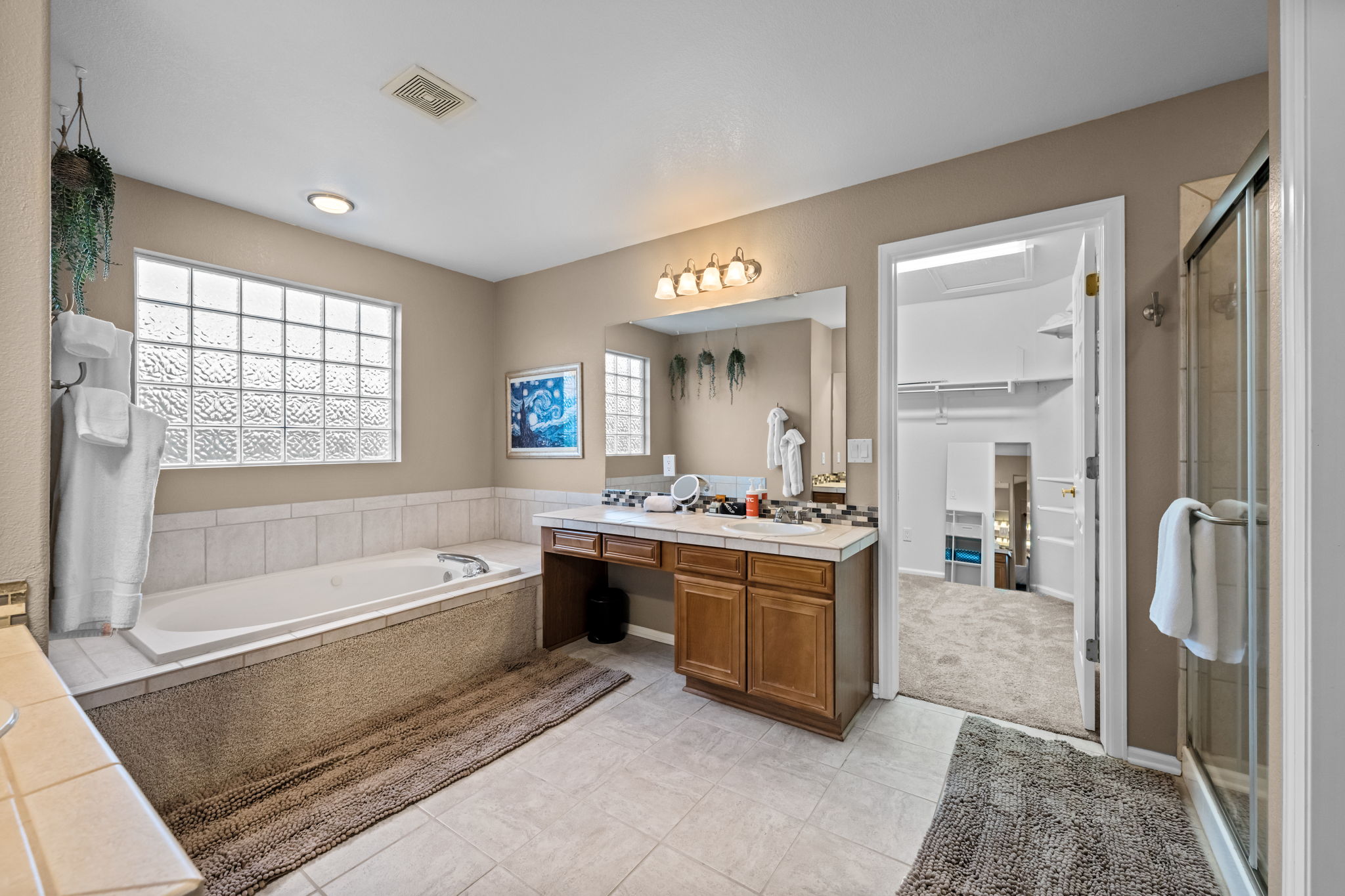 Primary bathroom ensuite with two separate sinks, bathtub with jets, separate shower, and walk-in closet