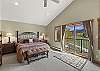 Main bedroom with king bed, ensuite bathroom, gas fireplace, Smart TV, remote workspace and balcony overlooking the third (3rd) tee box at the Rio Grande Club and Resort. 