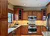 Fully-equipped kitchen with gas cooktop, oven, microwave, granite countertops, dishwasher, refrigerator, freezer, and more