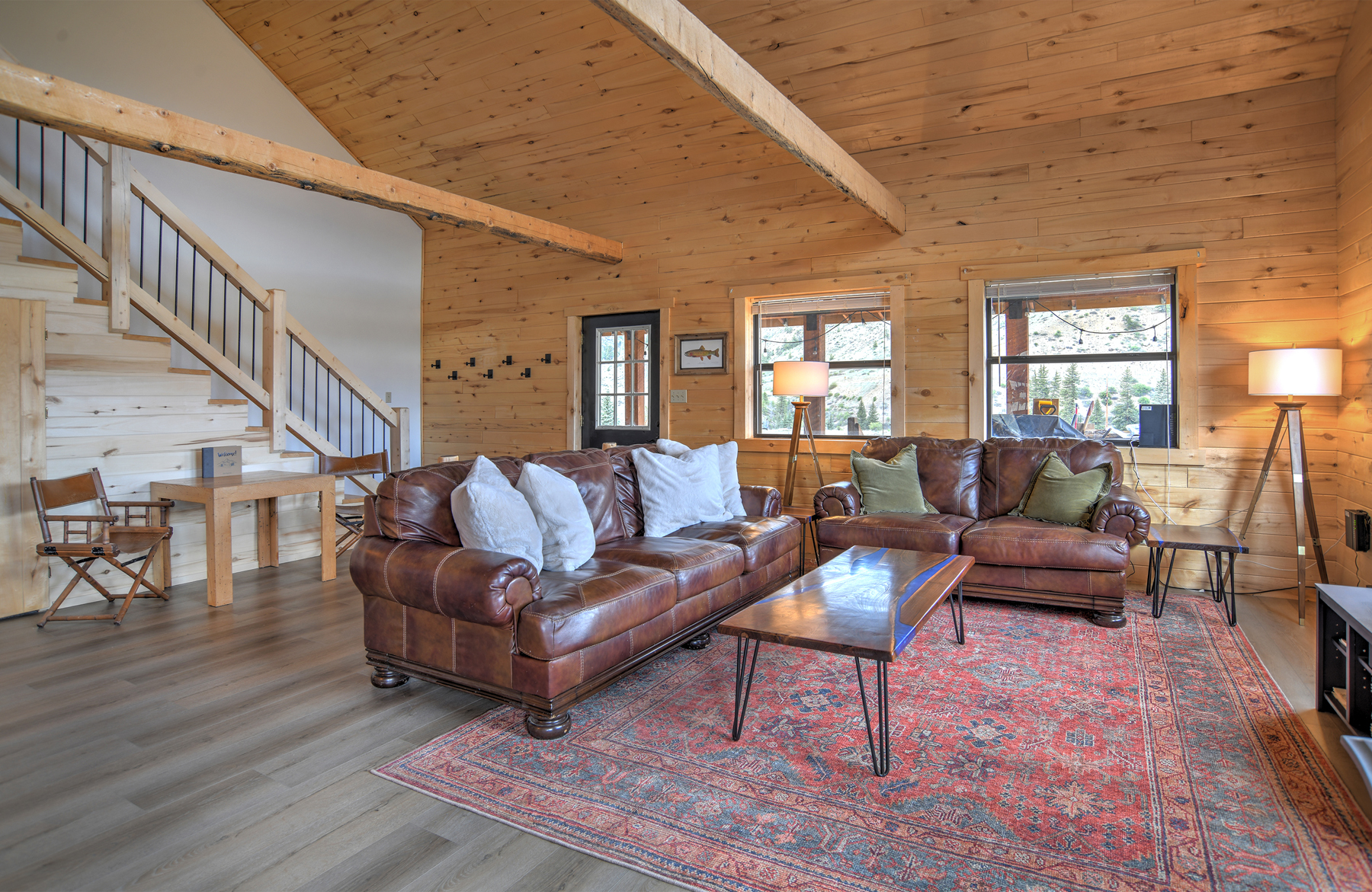 Open-concept living area featuring a spacious living room with a gas fireplace, Smart TV and puzzle table, a fully equipped kitchen with stainless steel appliances, a dining area with plenty of seating, and an open loft area above.