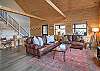 Open-concept living area featuring a spacious living room with a gas fireplace, Smart TV and puzzle table, a fully equipped kitchen with stainless steel appliances, a dining area with plenty of seating, and an open loft area above.