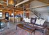 Open-concept living area featuring a spacious living room with a gas fireplace and Smart TV, a fully equipped kitchen with stainless steel appliances, a dining area with plenty of seating, and an open loft area above.