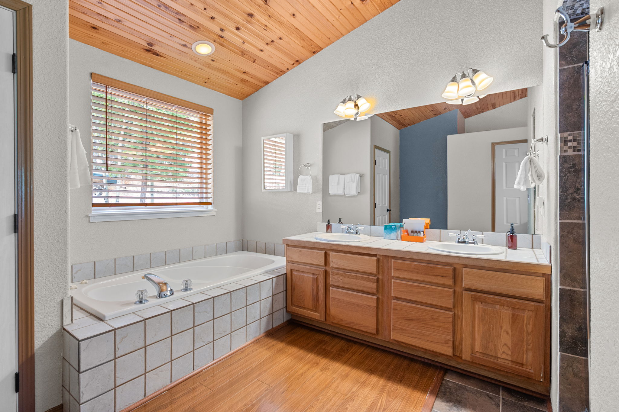 Full bathroom with dual vanities, soaking tub, and walk in shower