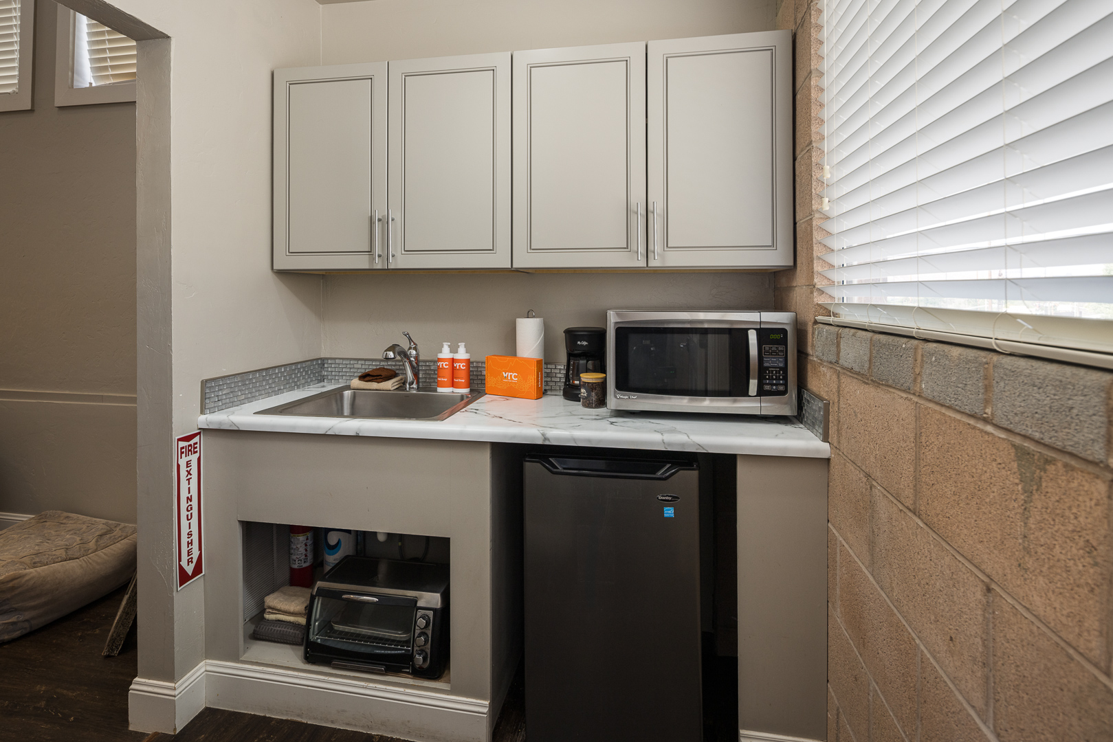 Kitchenette with a toaster, microwave, sink and mini fridge.
