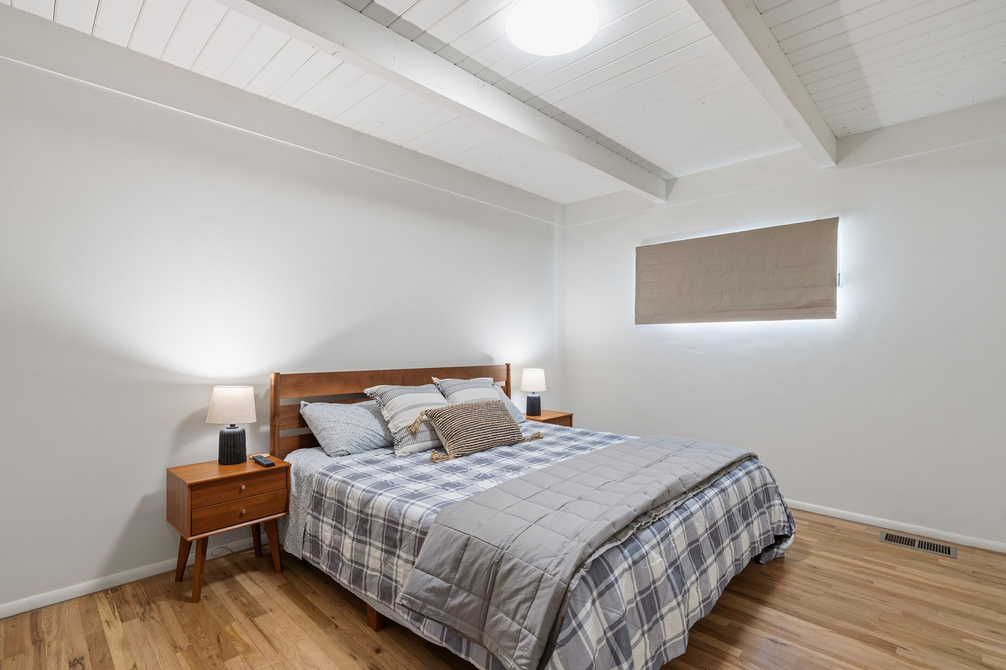 Second queen bedroom flooded with natural light and equipped with Smart TV