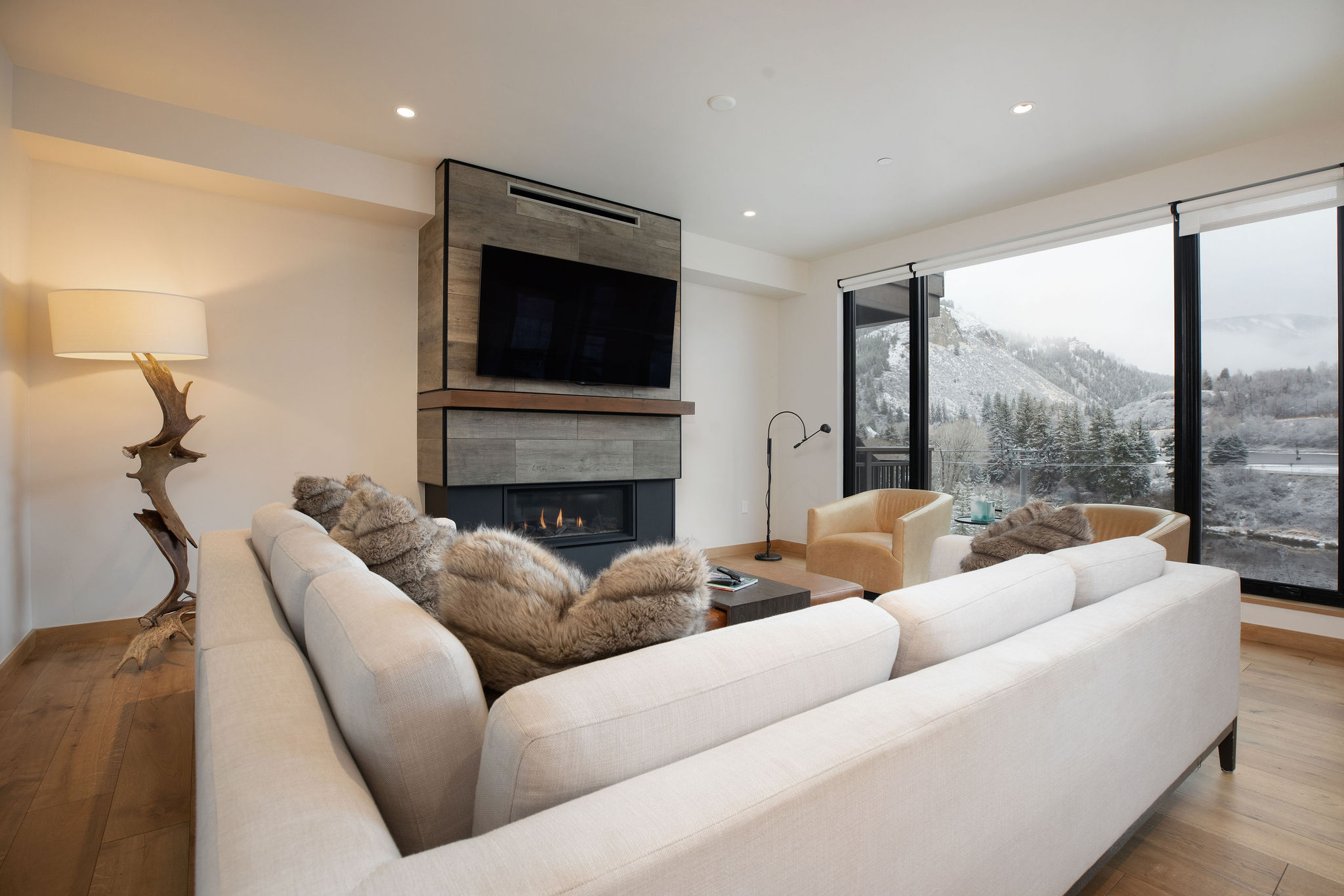 Open-concept living room with floor-to-ceiling windows showcasing breathtaking mountain vistas