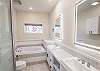 Full bathroom featuring dual vanities, a walk-in shower, and a bathtub
