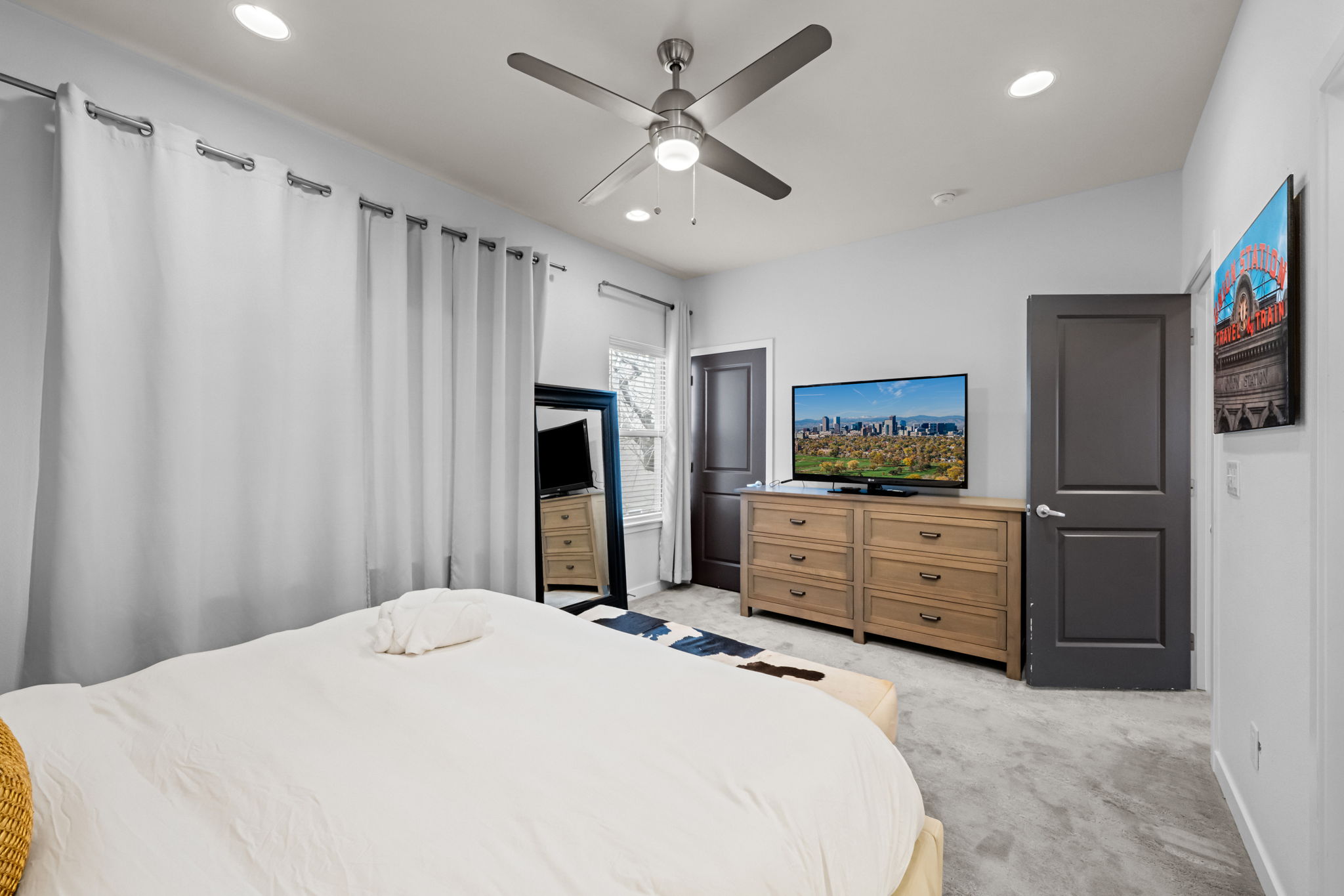 Clean modern bedroom with neutral tones and ceiling fan for year-round comfort