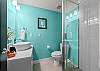 Bright turquoise bathroom with tub-shower combo—stylish and modern finishes
