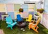 Backyard fire pit area with colorful Adirondack chairs for evening gatherings.
