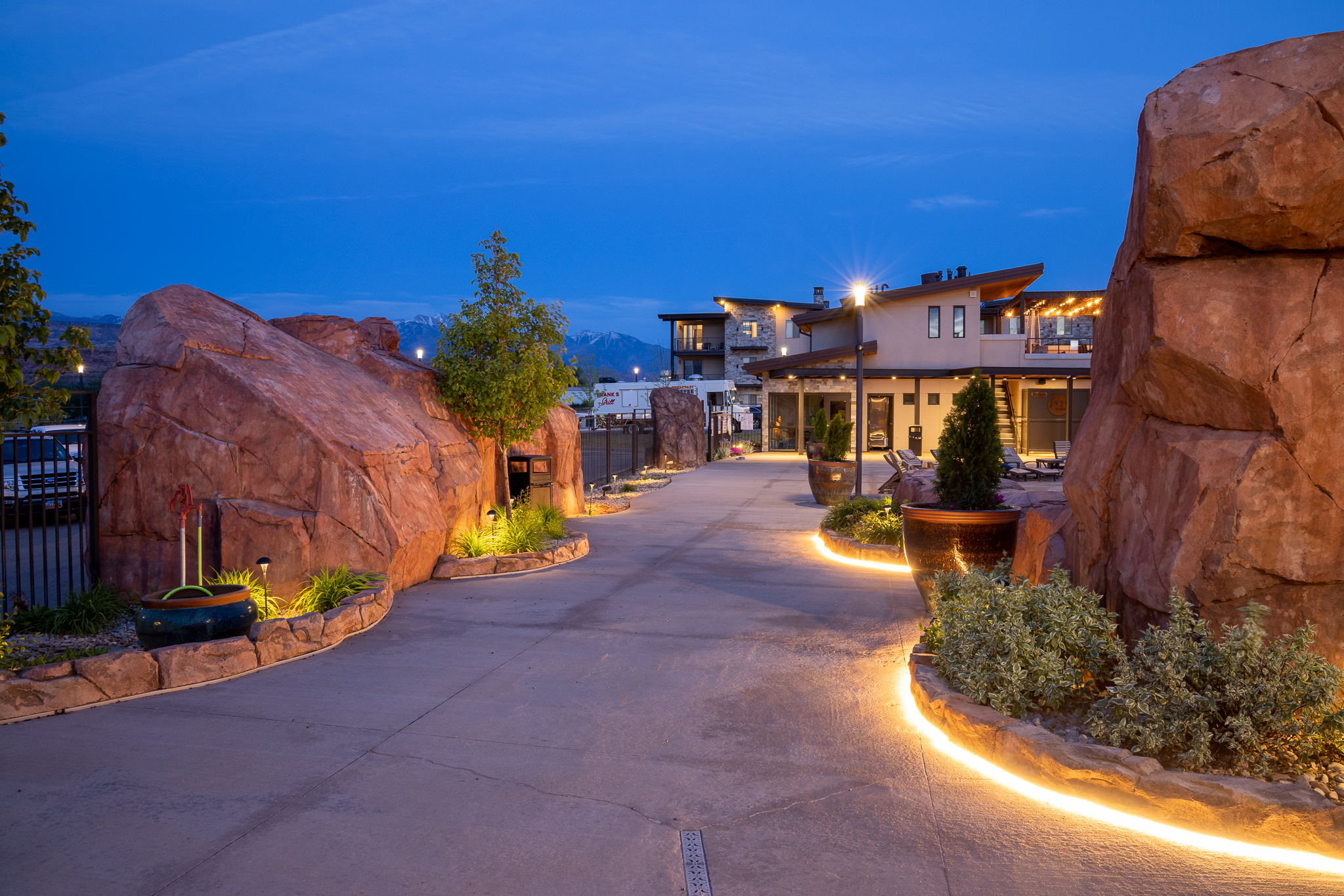 Beautifully landscaped entrance with red rock accents and welcoming lighting at dusk.