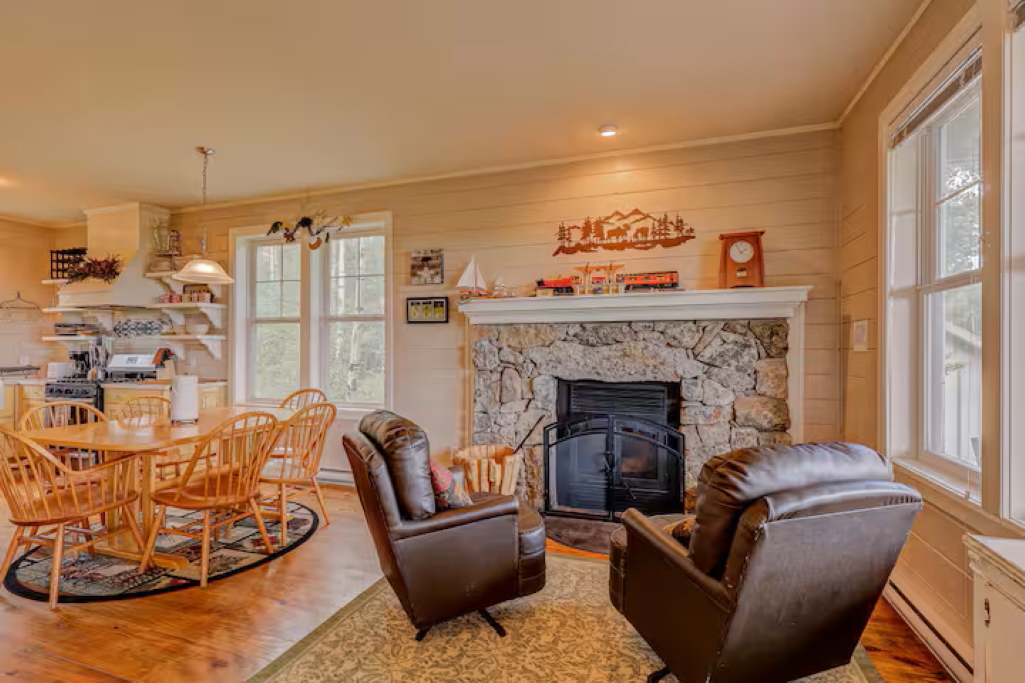 Open living and dining space with a stone fireplace and seating for friends and family gatherings.