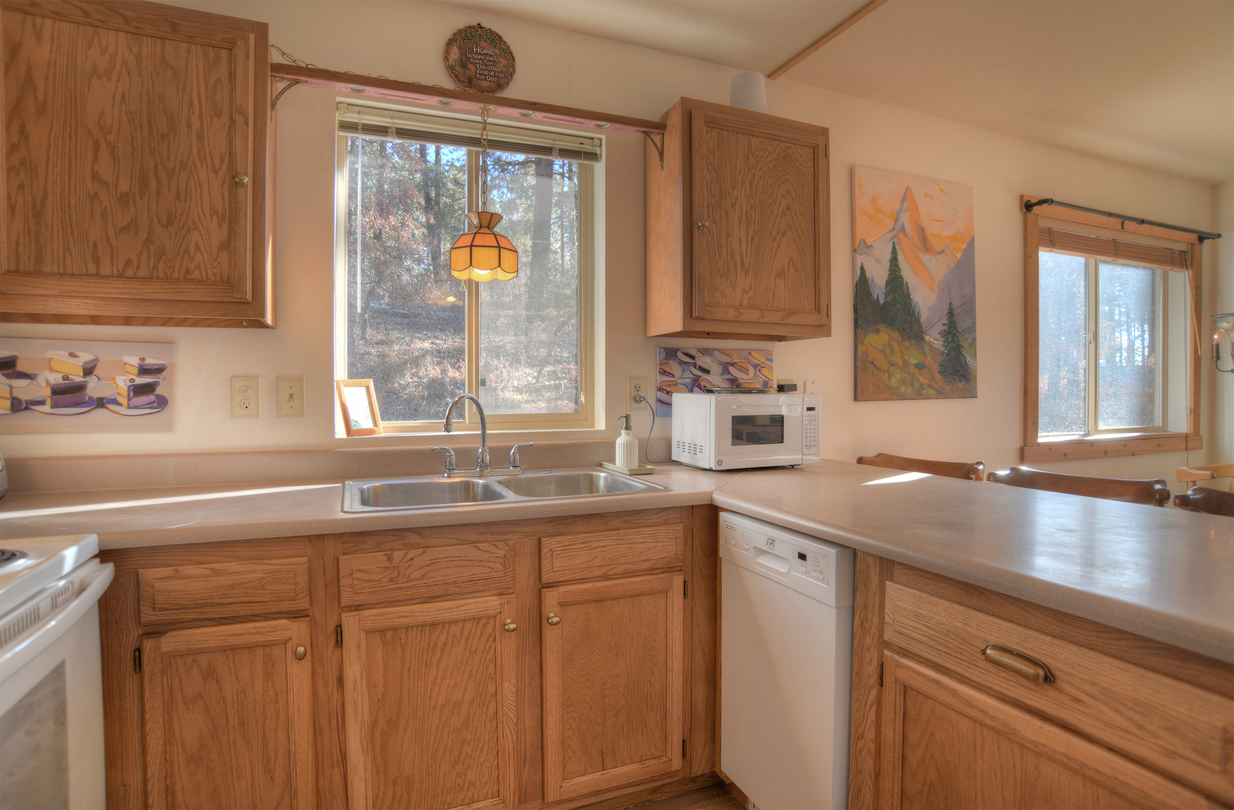 Kitchen with oak cabinetry and mountain views through the window – cook while enjoying the peaceful forest setting.