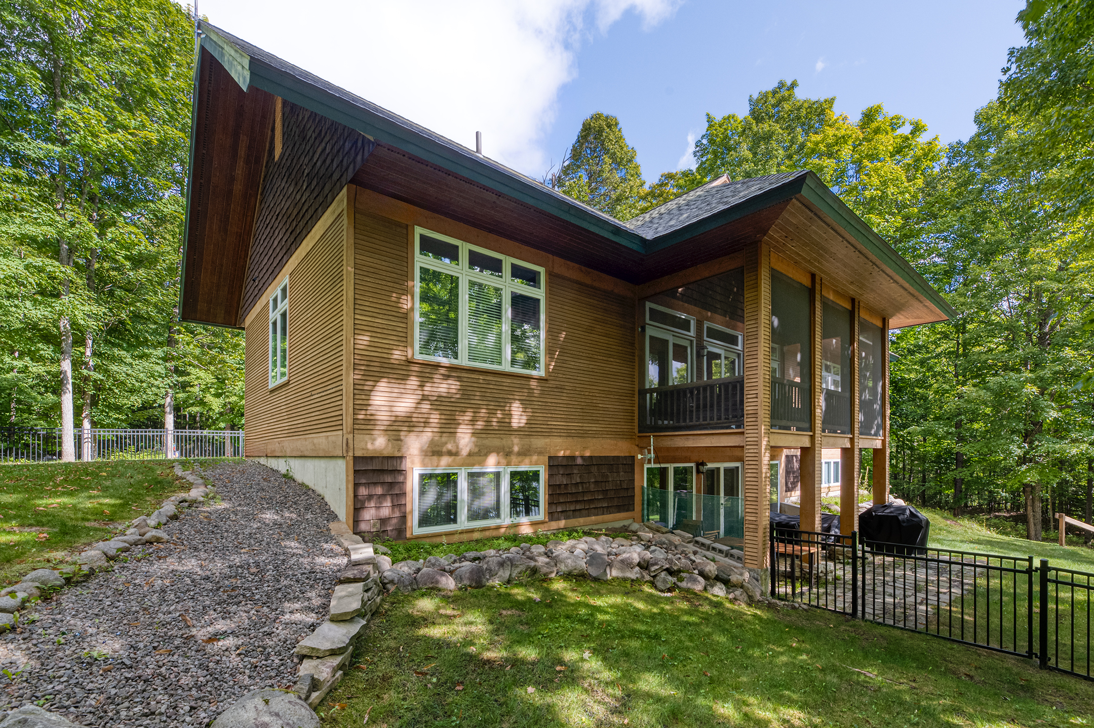 Lakefront exterior view with wraparound deck – plenty of outdoor space to enjoy the tranquil lake setting and Northwoods environment.