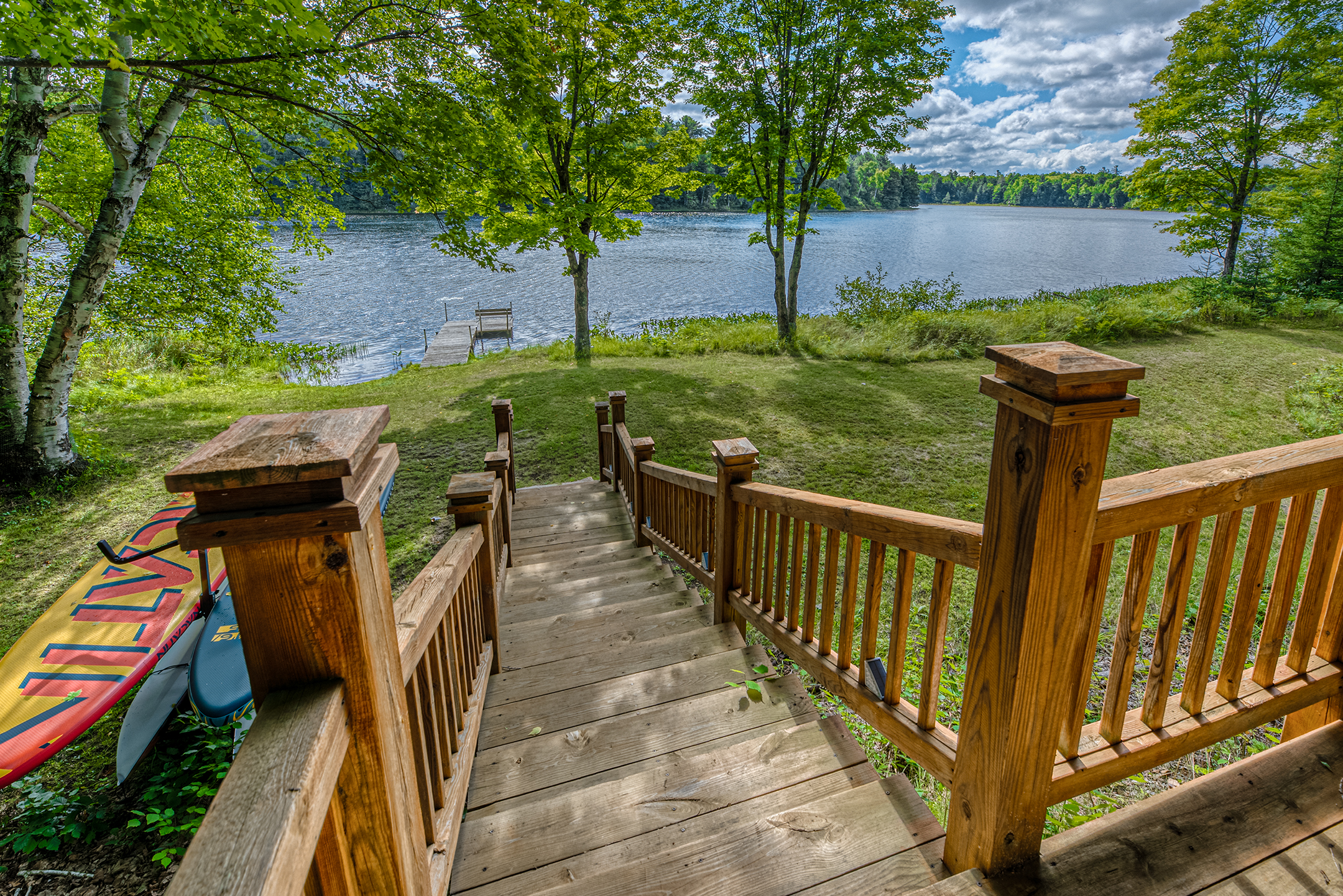 Scenic lakefront view with lily pads and mature trees – experience the natural beauty and serenity of Little Martha Lake from your private shore.