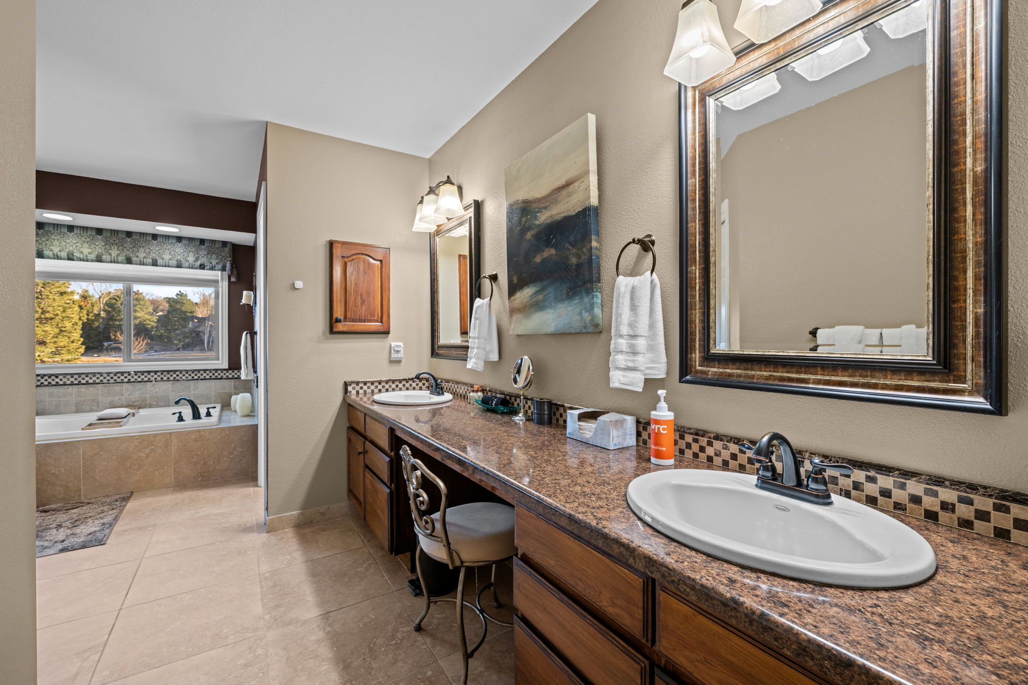 Spa-style primary bathroom with double vanity, soaking tub, and elegant finishes.