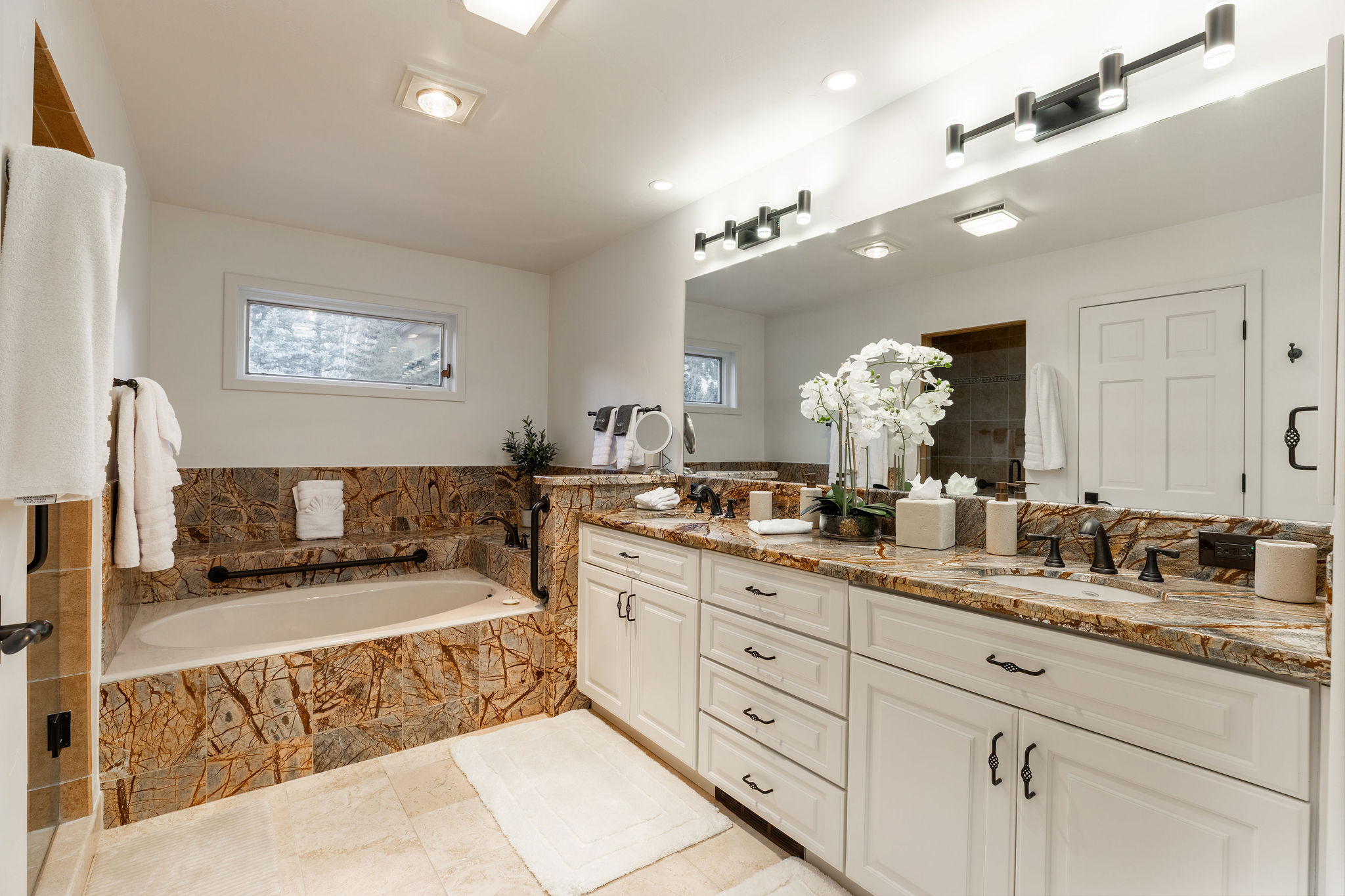 Full bathroom with dual vanities, a walk-in shower, and a soaking tub