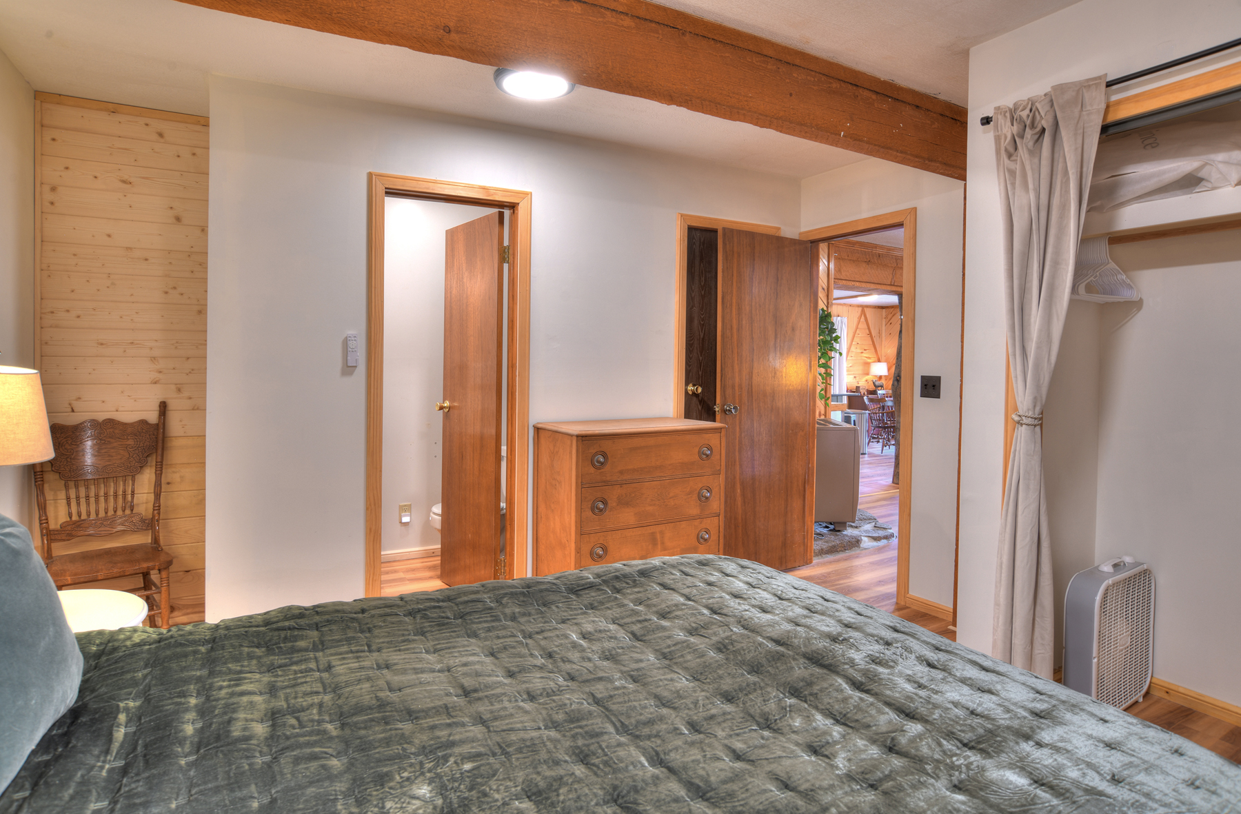 Second bedroom on the main level featuring a queen bed and a private half-bath ensuite.