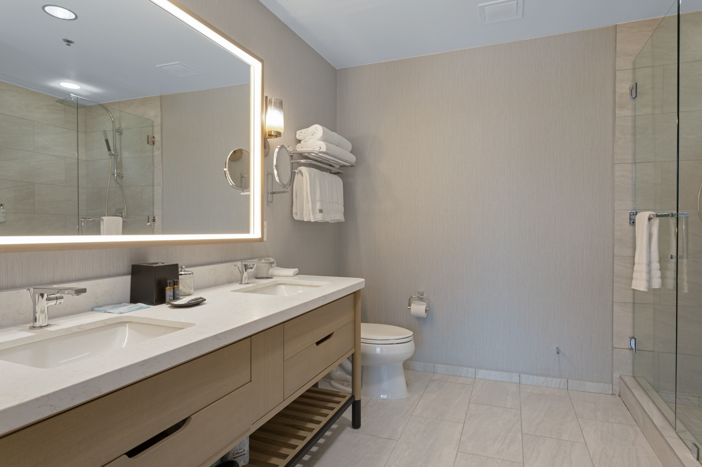 Full bathroom featuring a double vanity, large mirror, and a sleek walk-in shower.