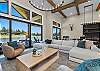 The open living room offers comfortable seating for the whole group, a gas fireplace, and Tanager Lake as the backdrop.