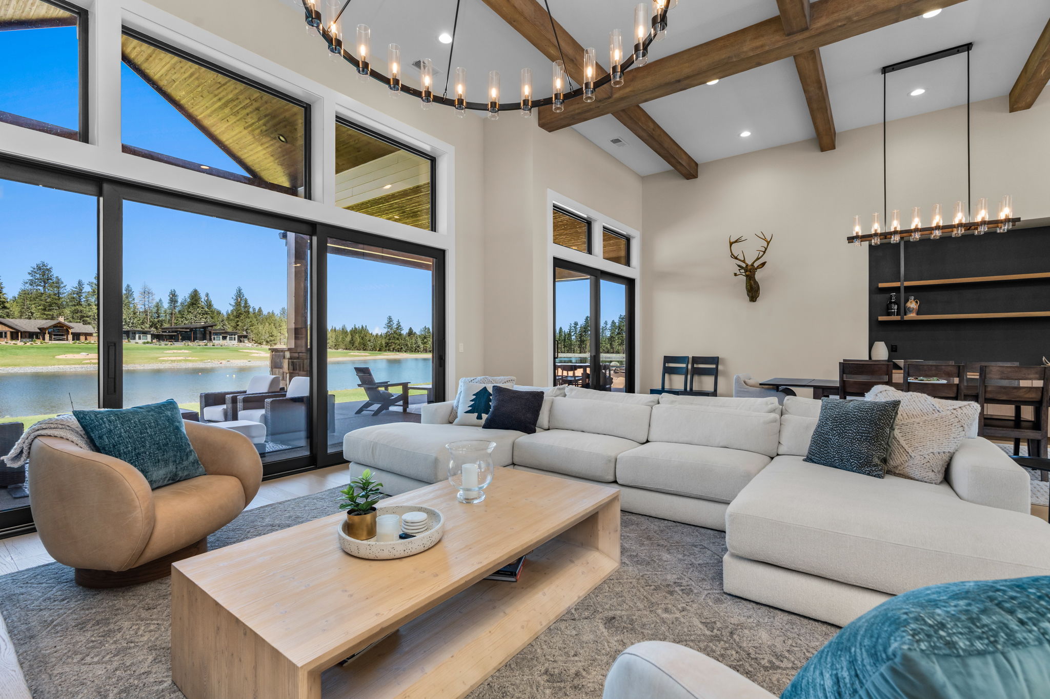 The open living room offers comfortable seating for the whole group, a gas fireplace, and Tanager Lake as the backdrop.