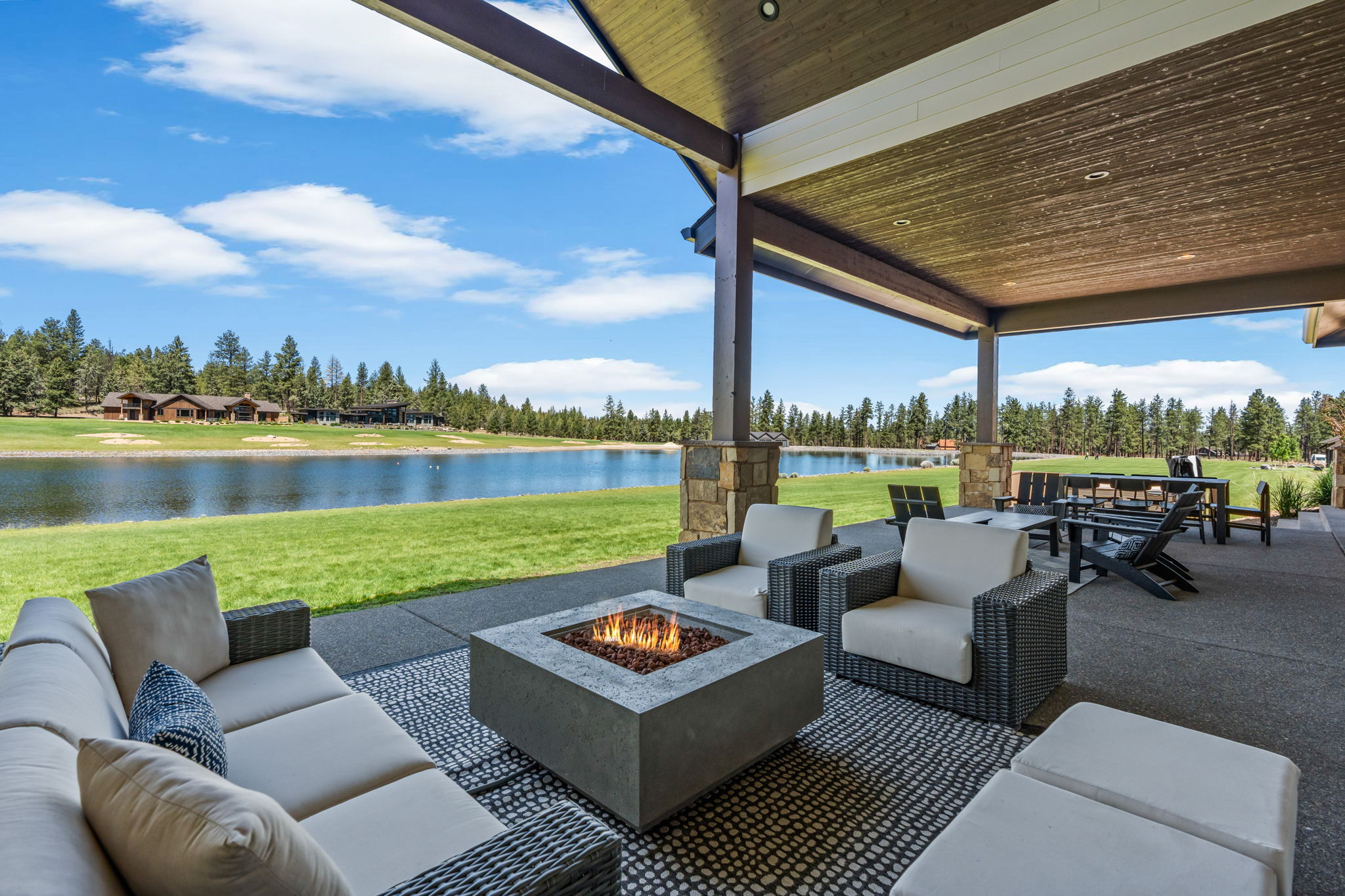 The covered outdoor patio is made for gathering — dining for 8, natural gas fire pit, private hot tub, space heater, and a natural gas BBQ, all with Tanager Lake as your backdrop.