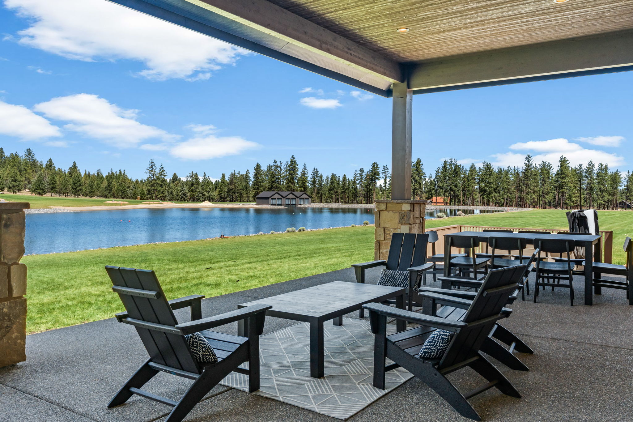 The covered outdoor patio is made for gathering — dining for 8, natural gas fire pit, private hot tub, space heater, and a natural gas BBQ, all with Tanager Lake as your backdrop.
